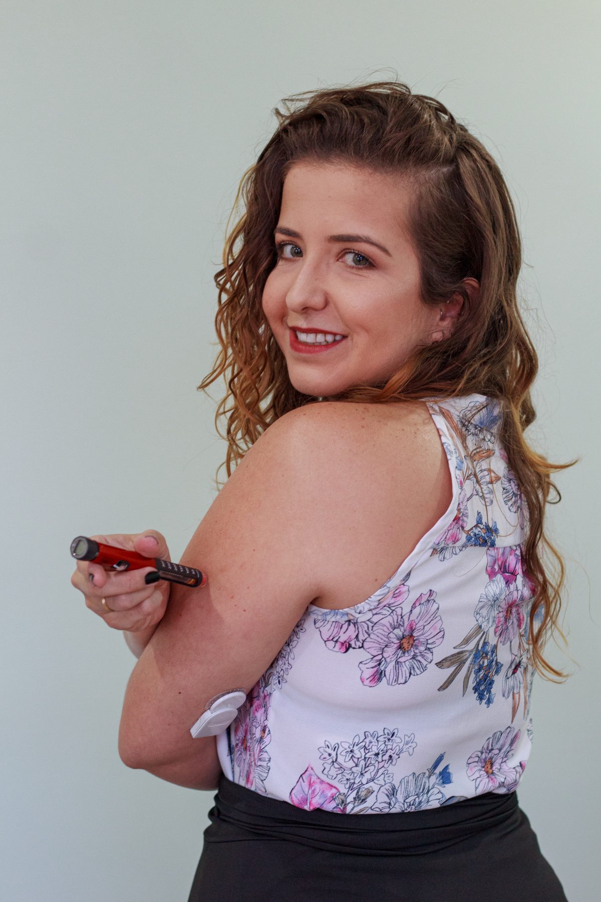 Letícia aplicando insulina, com sensor de glicose no braço